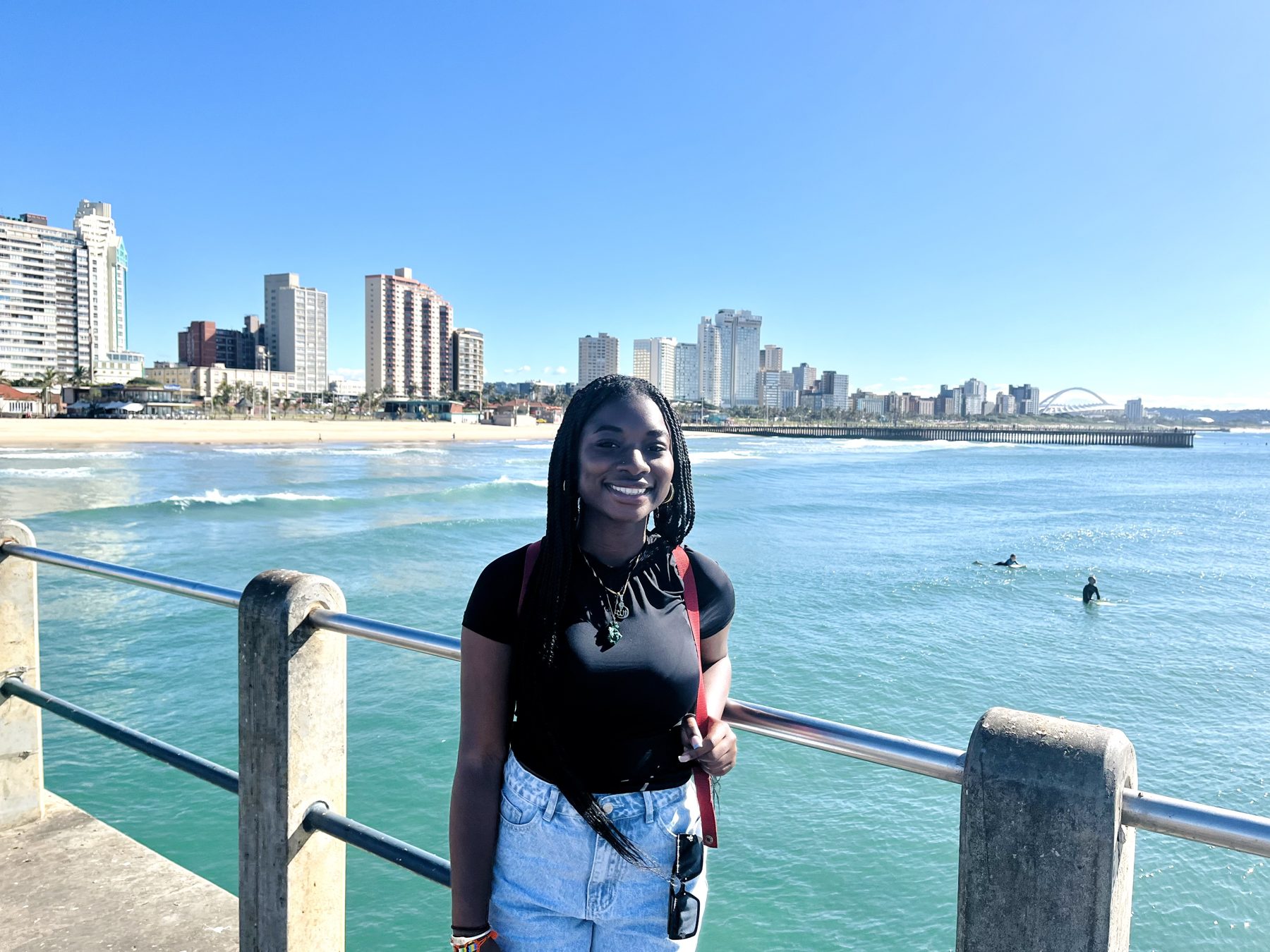A student on the Durban pier with the city skyline behind